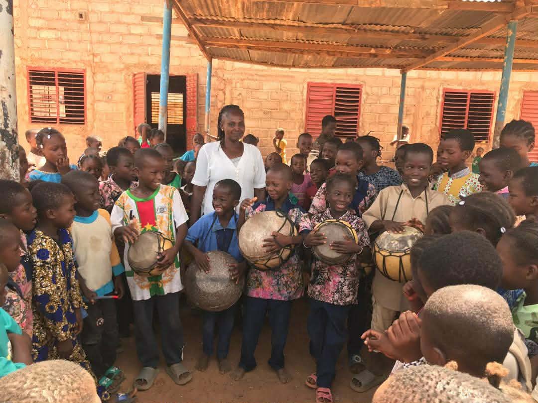 A teacher and children gathered with their instruments